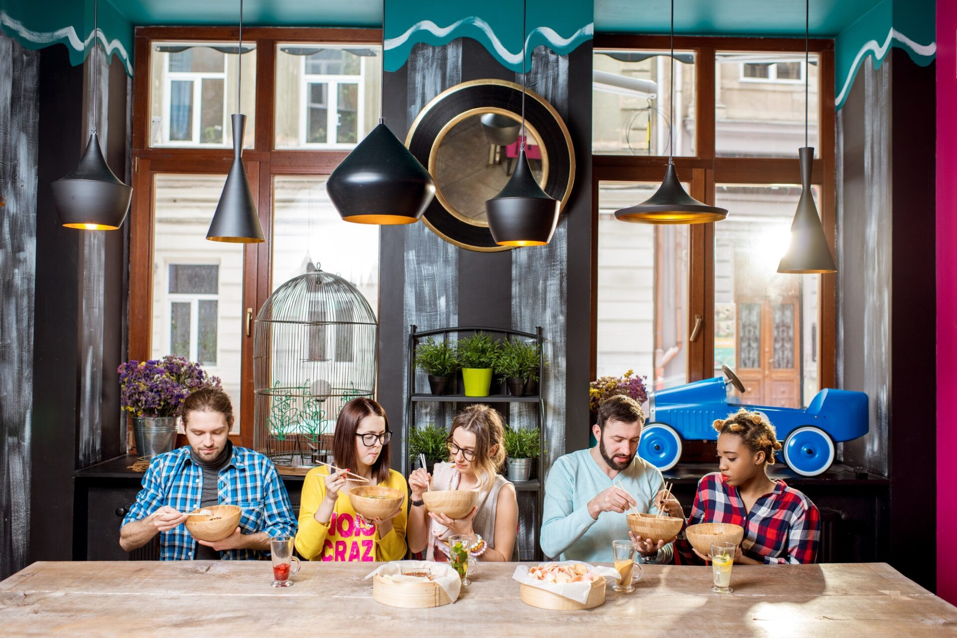 Jeune groupe de personnes assises de suite à la grande table pendant le dîner avec des repas asiatiques dans le restaurant moderne